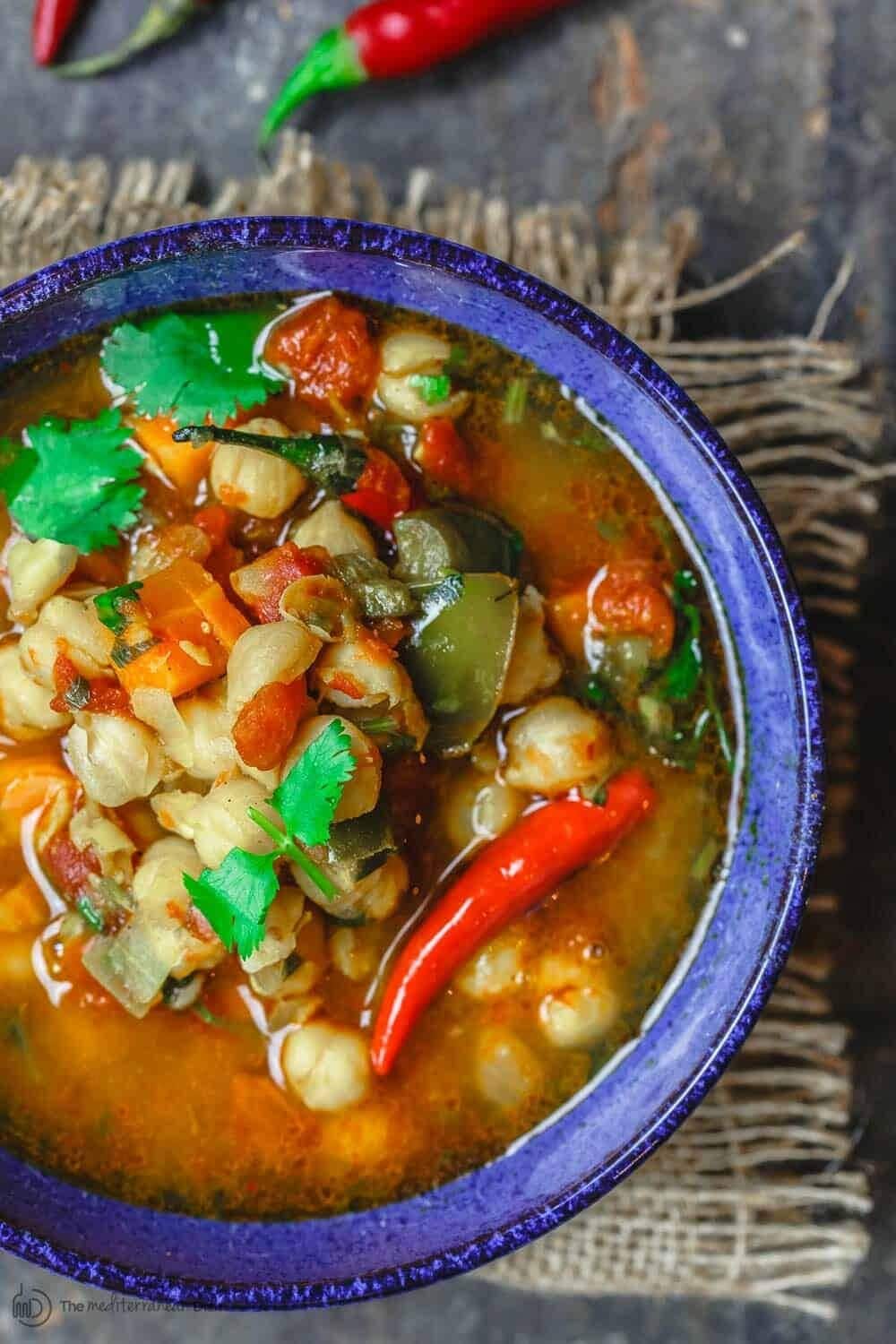 Bowl of homemade Instant Pot Chickpea Soup with chopped carrots, tomatoes, bell peppers, cilantro and red chili peppers