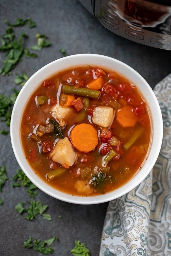 Bowl of homemade Instant Pot Vegetable Soup with carrots, potatoes, dice tomatoes, kale and fresh green beans