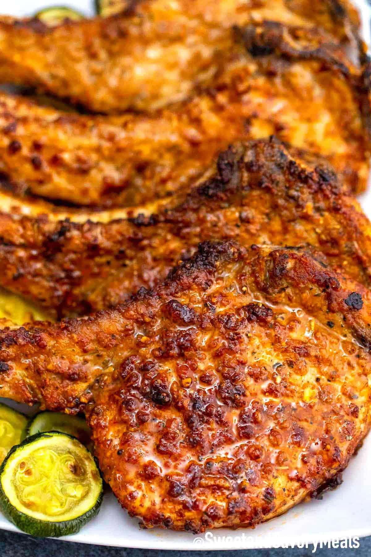 Homemade Air Fryer Pork Chops on a plate with sliced cucumbers on the side