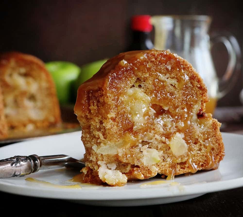 A slice of apple bundt cake drizzled with caramel syrup on top.