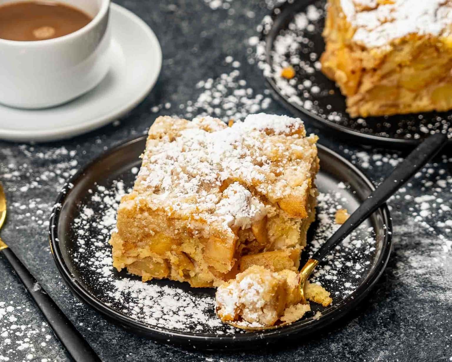 A slice of apple pie cake sprinkled with powdered sugar.