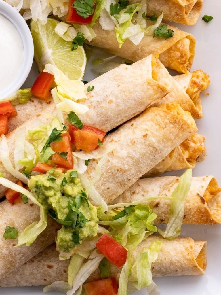 Bunch of Chicken Flautas serve them with sour cream, guacamole, shredded lettuce, and pico de gallo