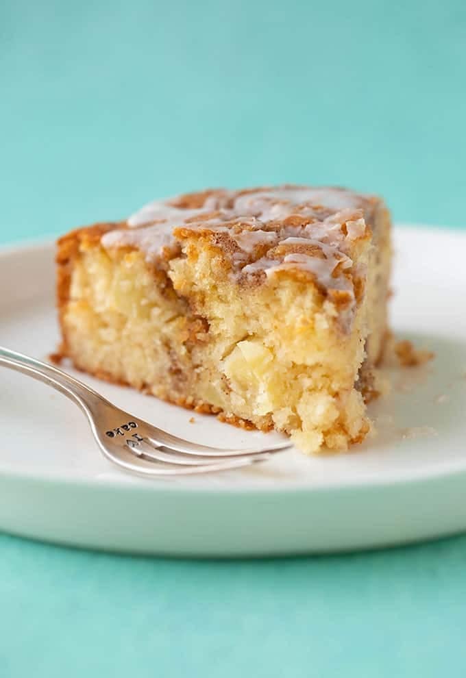 A slice of cinnamon apple cake on a white plate.