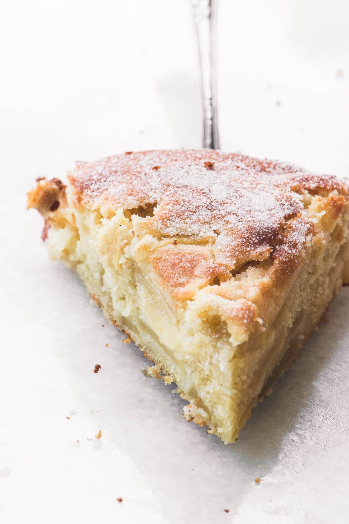 A piece of slice of Dutch apple cake with powdered sugar on top.
