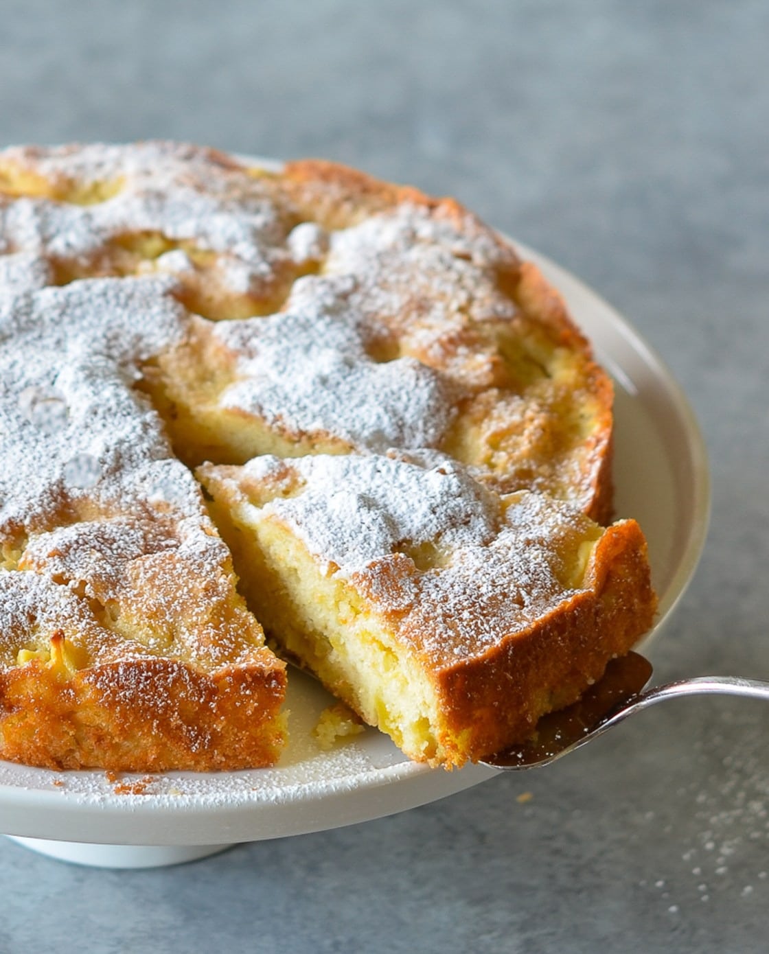 Sliced French apple cake with powder sugar on top.
