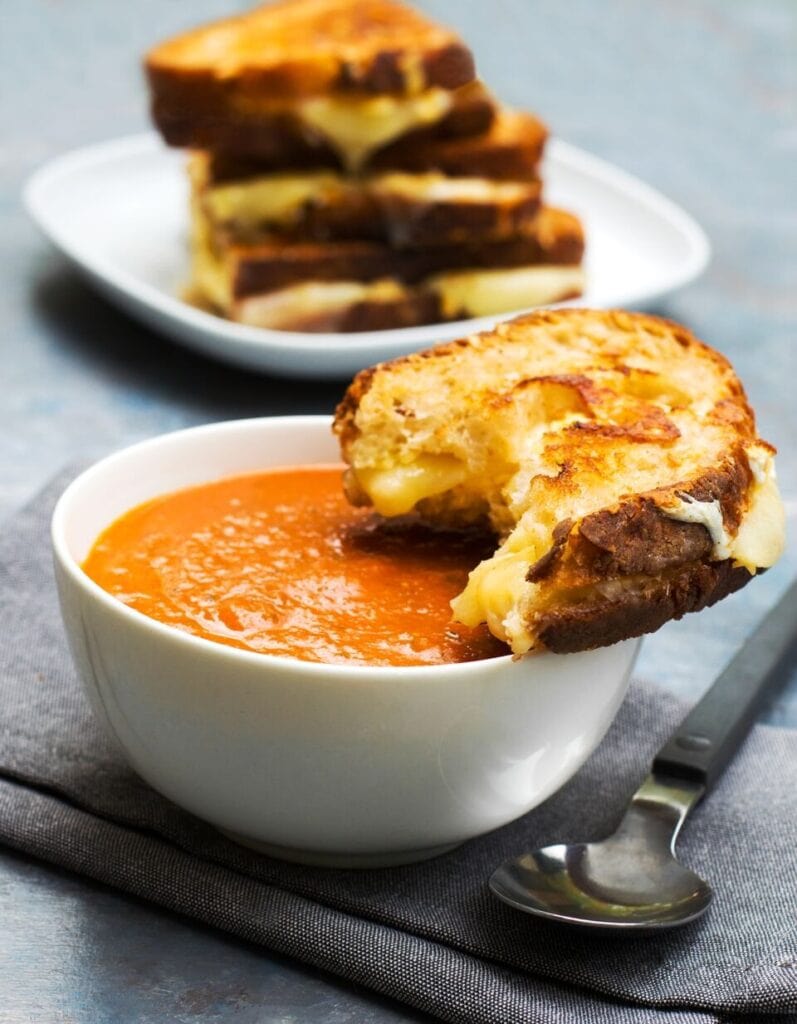 Tomato soup on a bowl with grilled sandwich with cheese.
