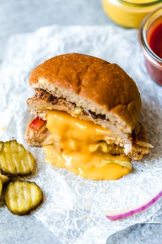 Turkey sandwich with cheese and pickles on a bun.