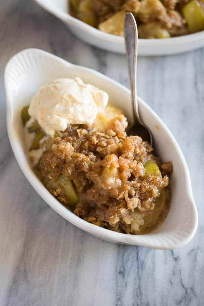 Apple crisp with vanilla ice cream on a bowl with spoon.