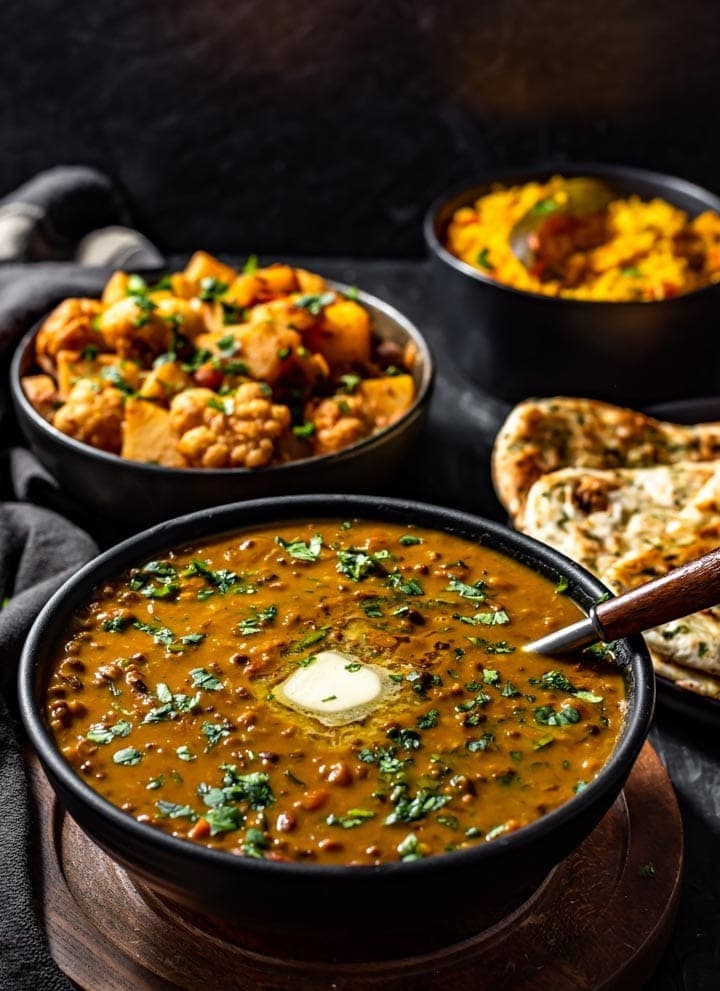 Bowl with dal makhani with a pinch of cream and chopped parsley on top.