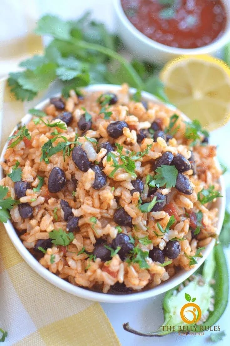 Rice and beans mix in a bowl garnished with chopped parsley leaves.