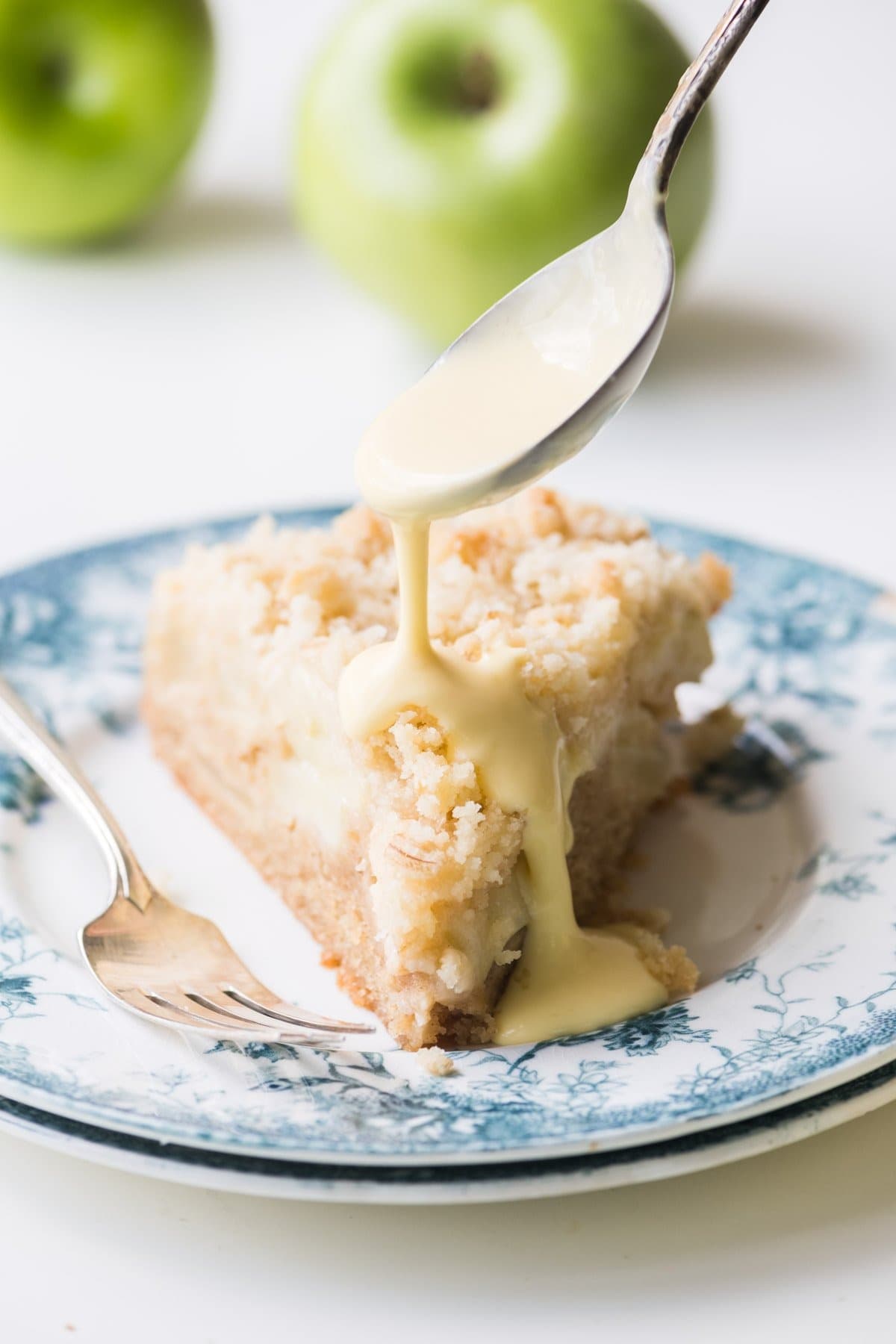 Slice of apple cake drizzled with custard sauce.