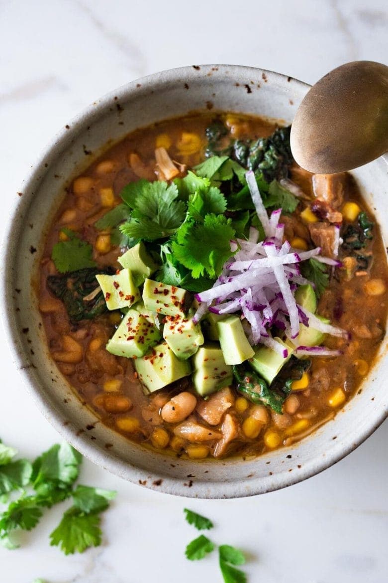 Chili topped with sliced avocado and red onions.