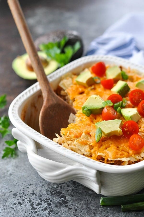 Nacho casserole topped with sliced avocadoes and cherry tomatoes