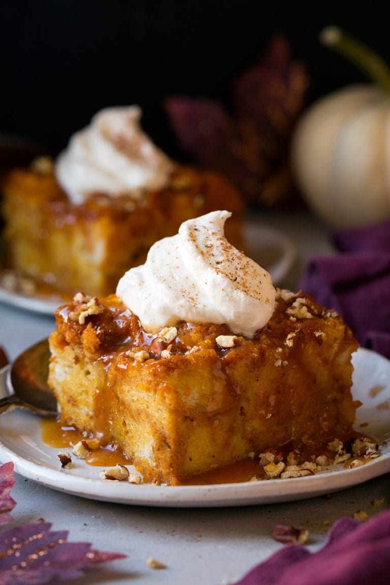 Slice of pumpkin bread pudding with vanilla on top sprinkled with cinnamon powder and chopped nuts.