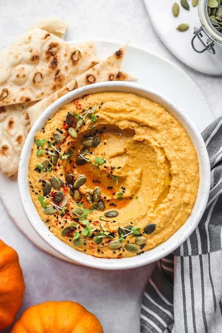 Bowl of pumpkin hummus topped with pumpkin seeds.