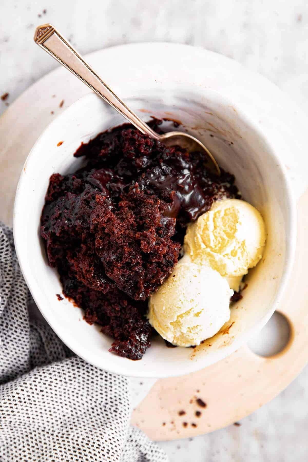Serving of chocolate pudding in a bowl with two scoops of vanilla ice cream.