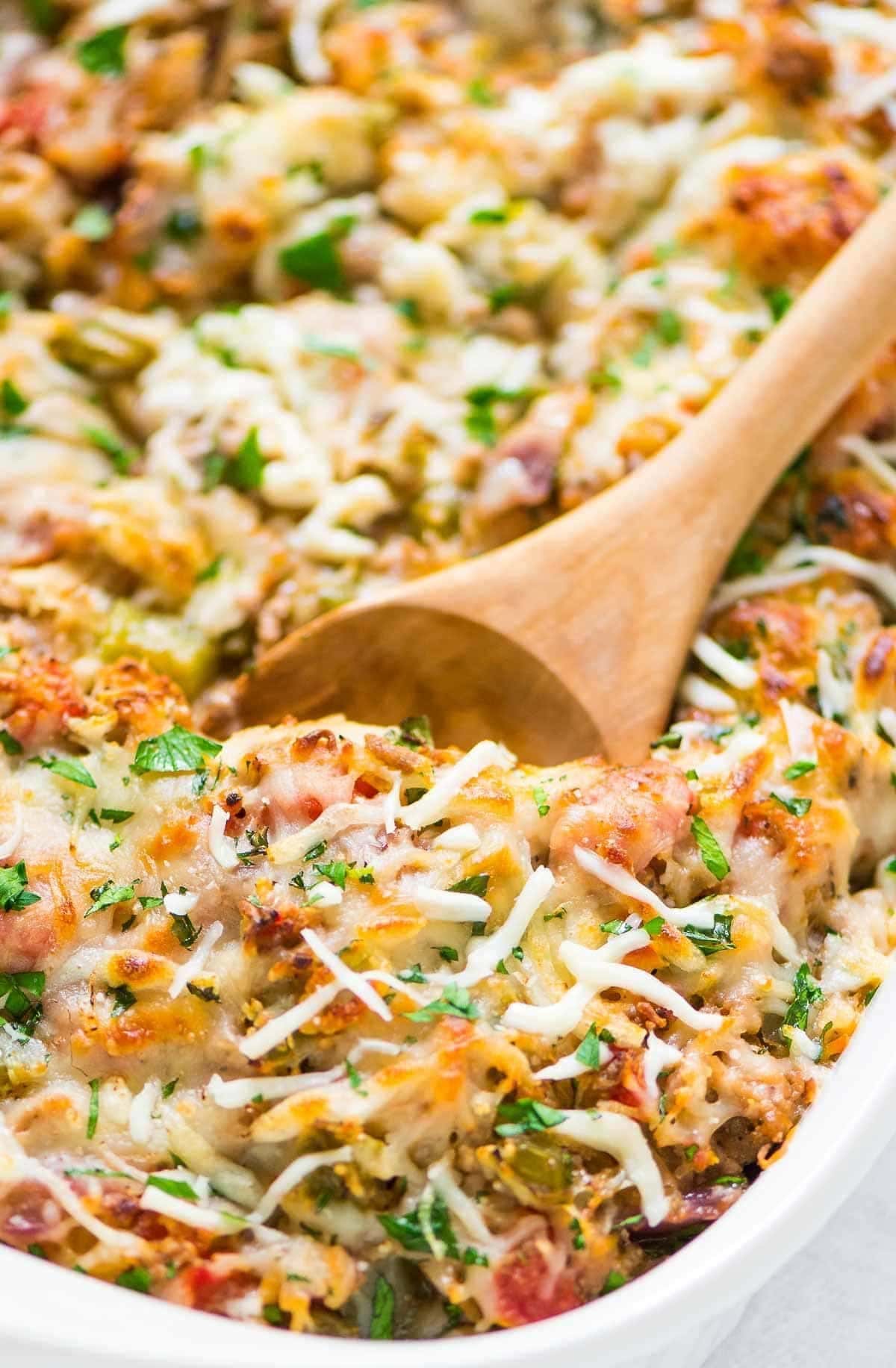 Wooden spoon scooping spaghetti squash in a casserole dish.