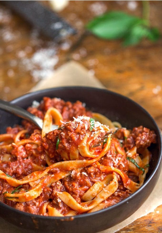 Pasta with turkey ragu sauce served on a black bowl with fork.