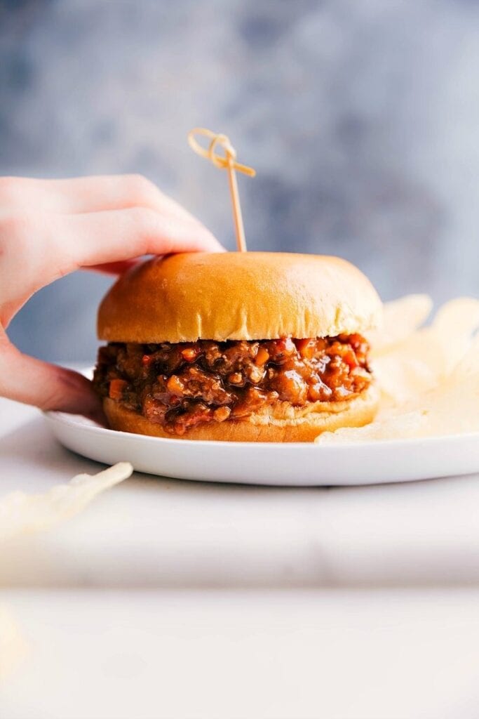 Hand holding a bun sandwich with ground turkey filling.