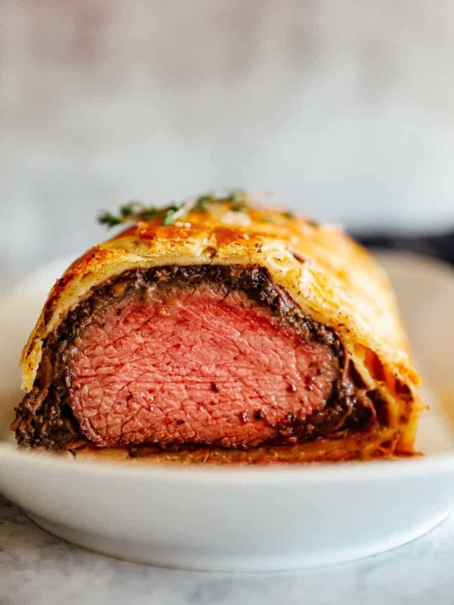 Beef wellington sliced served on a plate.