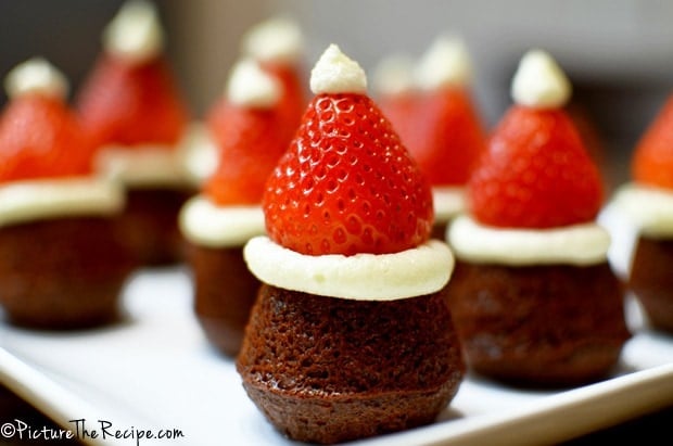 Mini brownies topped with strawberries and frosting.