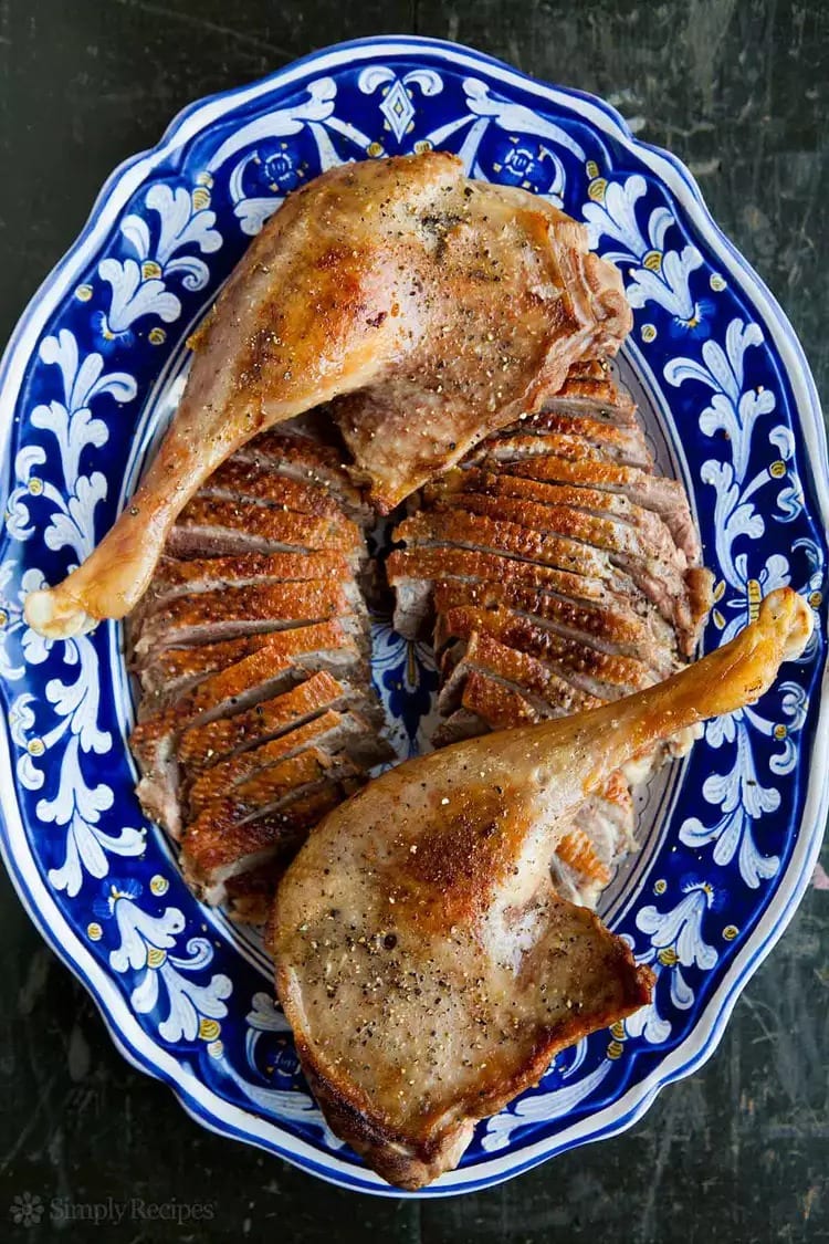 Sliced roasted goose thighs served on a plate.